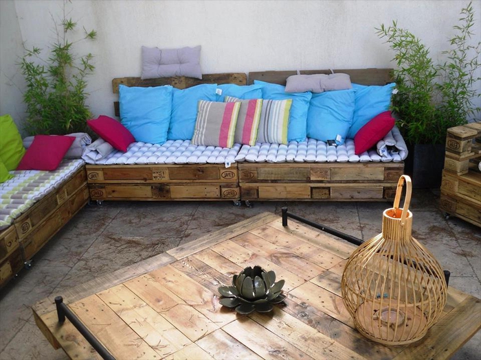 un salon de jardin fabriqués entièrement en palettes acec des coussins et , des meubles palettes de jardin fonctionnels et confortables