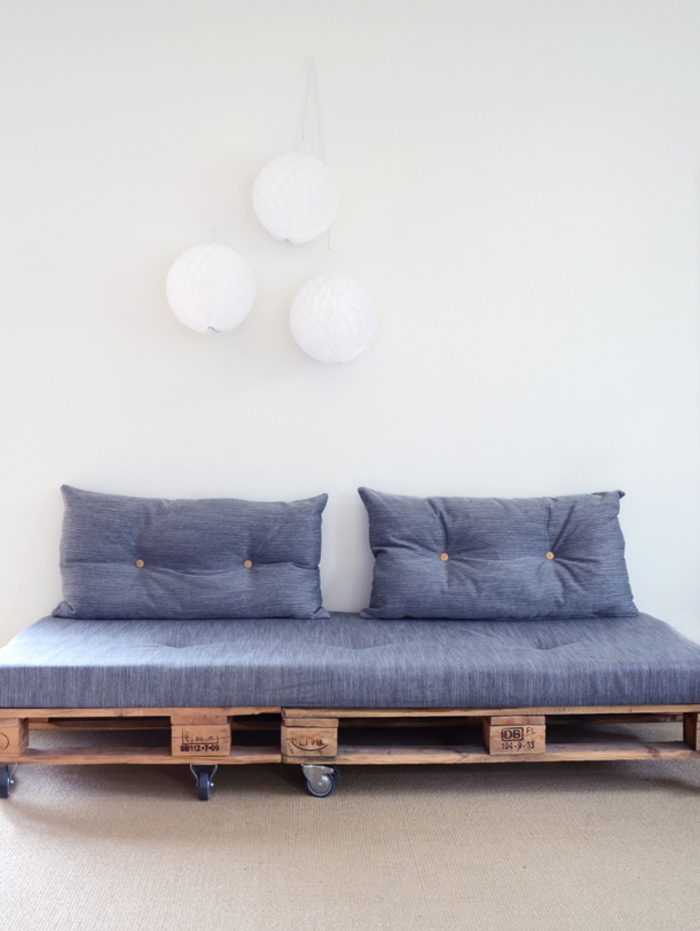 un petit canapé en palette avec roulettes, matelas et coussins matelassés idéal pour l aménagement d un salon moderne de style scandinave