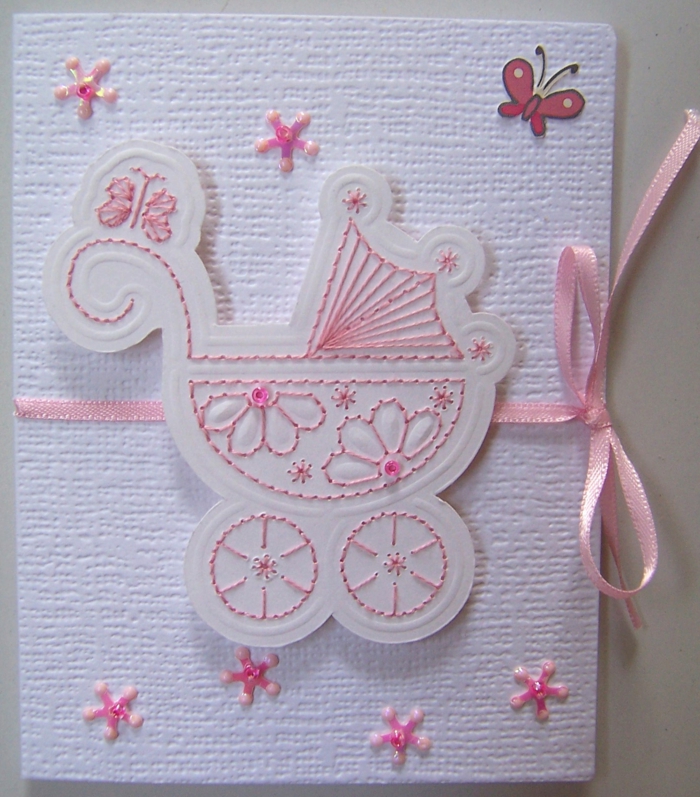 carte avec un landeau pour la naissance d'un bébé fille, ruban rose et autres broderies