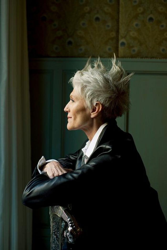 coupe cheveux courts, couleur cendres, avec des crêtes formées avec du gel sur le haut, style de coiffure rock et punk, femme âgée dans un décor baroque 