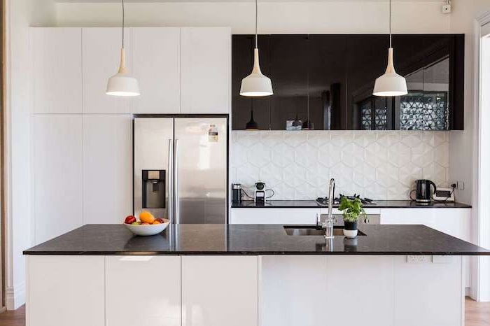 cuisine moderne blanche et noire, credence cuisine blanche a motifs geometriques effet 3 d, plan de travail et meubles hauts noirs, parquet marron, suspensions blanches