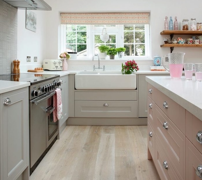 cuisine equipee avec meuble bas gris et lavabo blanc, ilot central rose, parquet clair, poele inox et etageres ouvertes en bois et metal