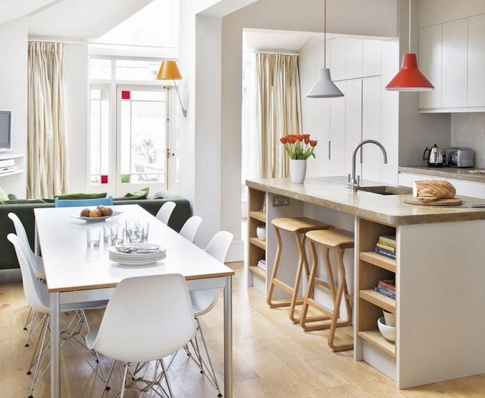 cuisine amenage avec meuble blanc, ilot central avec plan de travail gris, parquet clair, petite salle à manger en table et chaises scandinaves