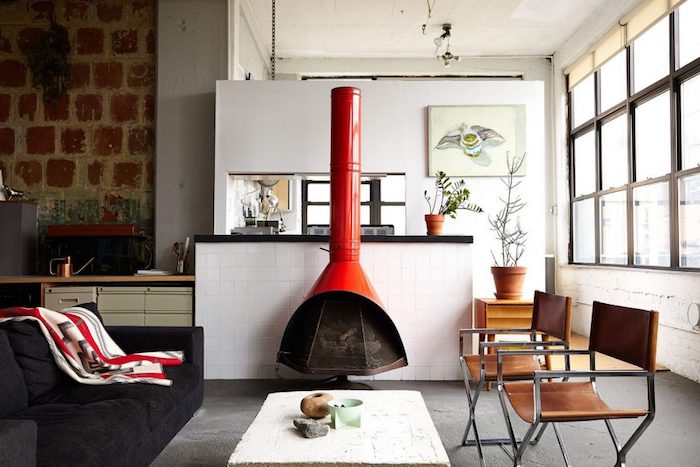meuble style industriel, chaises en cuir et métal, revêtement sol gris, canapé noir et cheminée rouge