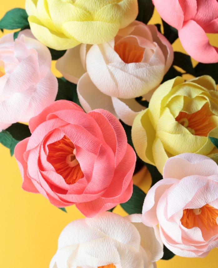 fleurs en papier crépon, pivoines couleur rose et jaune avec des feuillages vertes, petales rose, jaunes et blanches