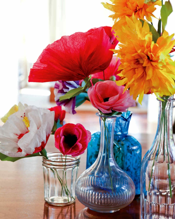 des dleurs en papier crépon et en papier de soie dans un vase, pot et bouteille en verre, fleurs couleur rose, rouge et jaune simples