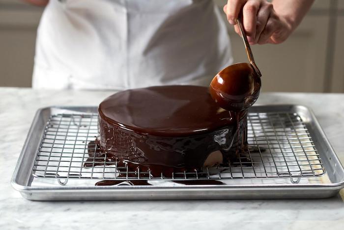 technique et recette pour faire le meilleur glacage miroir chocolat, exemple comment verser du chocolat noir liquide sur le gâteau