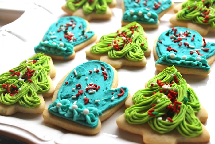 idée de sables de noel, biscuits en formes diverses, motif gant et sapin décoré de glaçage au beurre bleu et vert et vermicelles rouge et blanc, recette de glacage