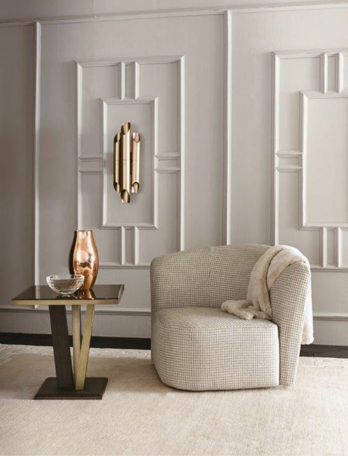 salon de luxe avec fauteuil semi-rond en couleur blanc crème, murs en blanc, avec des frises en forme de rectangles blancs, table carrée en blanc et noir, tapis en beige, vase décoratif en bronze 