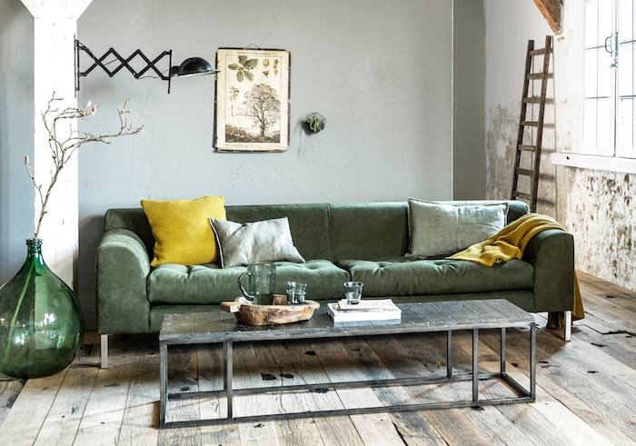 modele de petits salon industriel avec canapé vert coussins gris et jaune, table basse en bois et metal, parquet bois brut, echelle decorative, murs usés