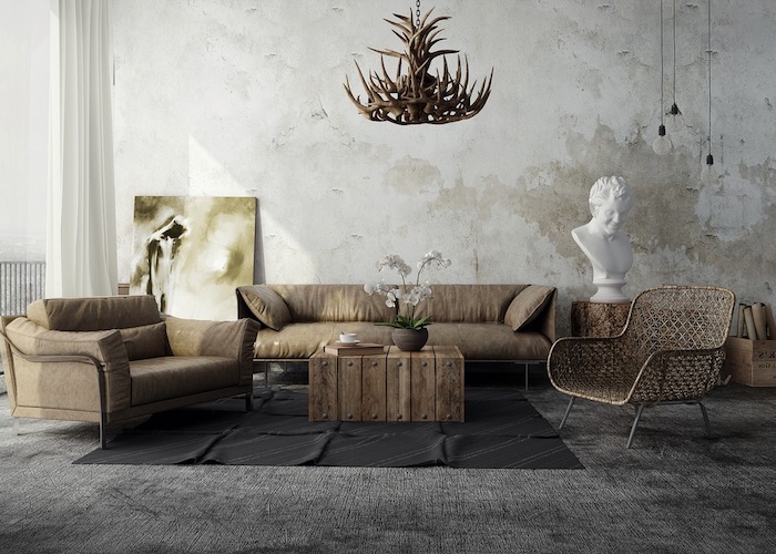 exemple de salon industriel artistique avec canapé et fauteuil gris, chaise originale, tapis gris, mur usé, lustre de bois de cerf, petite table basse en bois brut