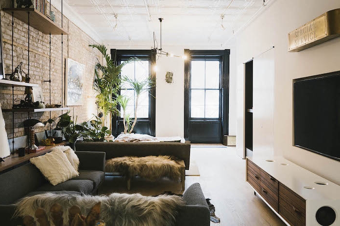 modele d etagere industrielle salon avec canapés gris, peaux animal, meuble tv industriel mur en briques, plantes