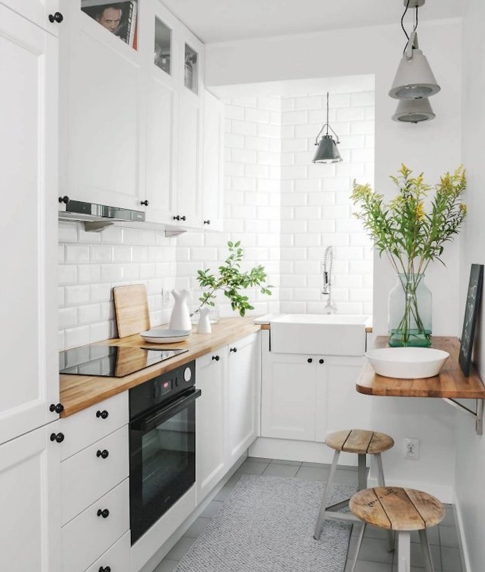 modele de cuisine blanche équipée avec meuble haut et meuble bas blanc, plan de travail bois, credence et mur carrelage blanc