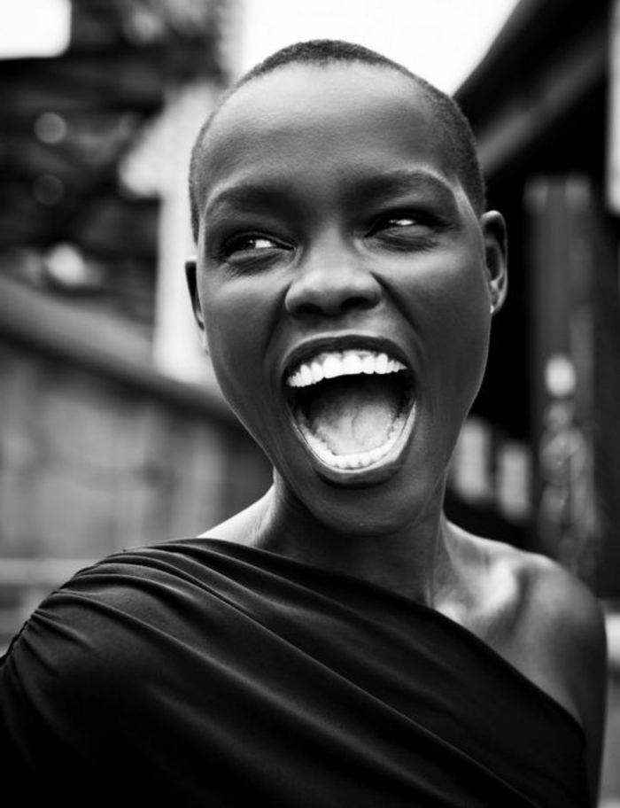 portrait noir et blanc, photo en noir et blanc, femme noire qui rit bien fort, les yeux riants, la tete presque râsée