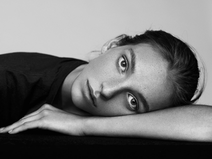 portrait noir et blanc, femme couchée sur son bras, photo en noir et blanc, yeux tristes, pose pensive, grands yeux expressifs