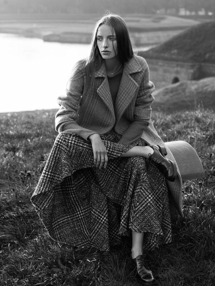 photo femme noir et blanc, tweed et longue jupe large à carreaux écossais, paysage nature avec lac sur le fond, soleil timide