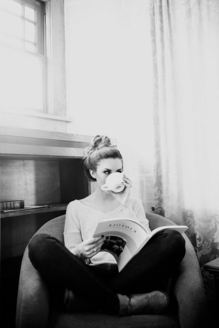 photo en noir et blanc, photo femme noir et blanc, jeune femme qui boit son café assise dans un grand fauteuil, un magazine à la main, appartement parisien chic