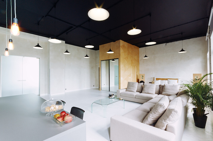 exemple d amenagement salon loft industriel, canapés gris, sol blanc et plafond noir, suspensions industrielles, table basse en verre