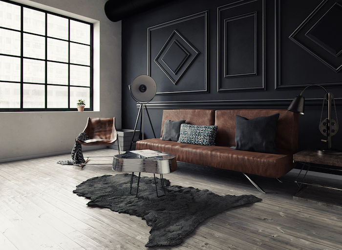 meubles style industriel dans un salon loft avec mur noir à motifs geometriques, canapé en cuir, peau animale noire, table basse originale, fauteuil en cuir, parquet gris