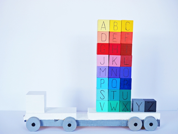 des cubes colorés en bois avec les lettres de l alphabet à ranger sur une plateforme de camion, montessori methode
