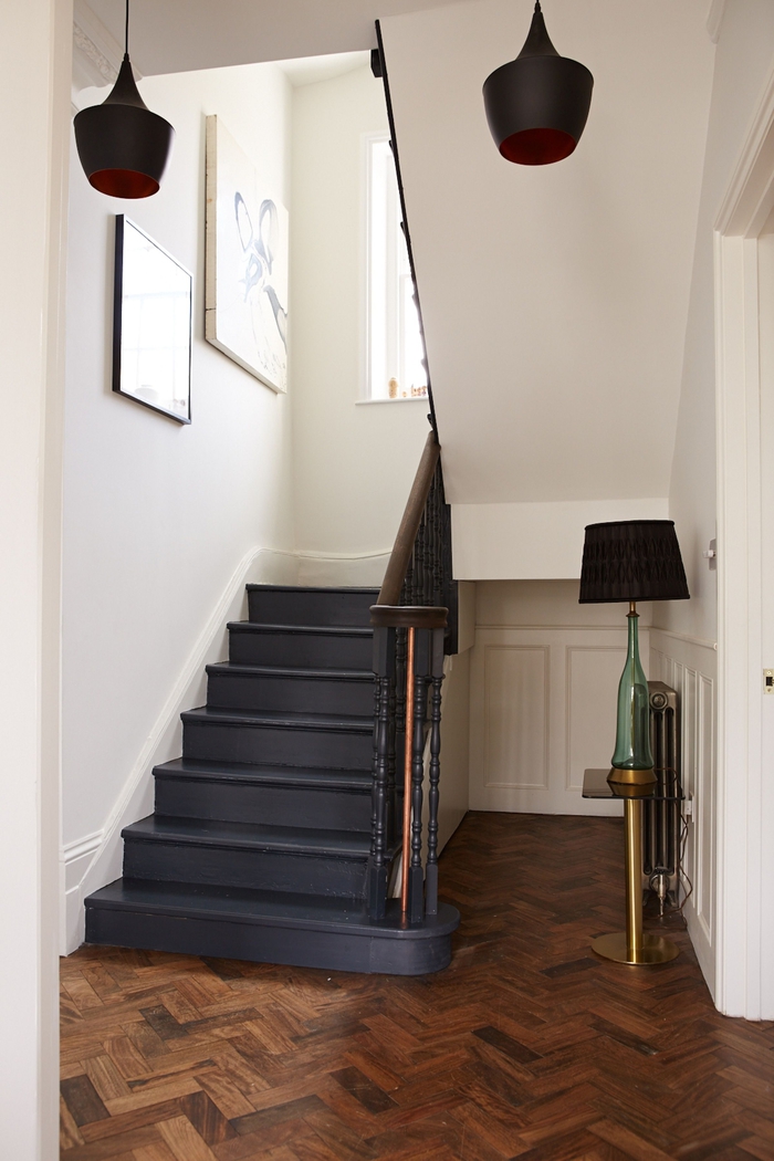 un escalier repeint en noir d'espace restreint en contraste avec l'intérieur blanc monochrome et l'ambiance scandinave épurée