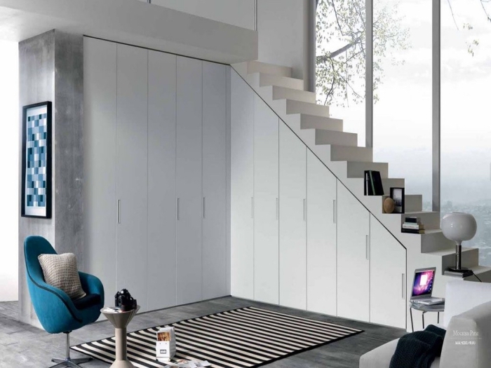 idée rangement sous escalier avec portes blanches, accessoires décoratifs tapis blanc et noir et coussin gris