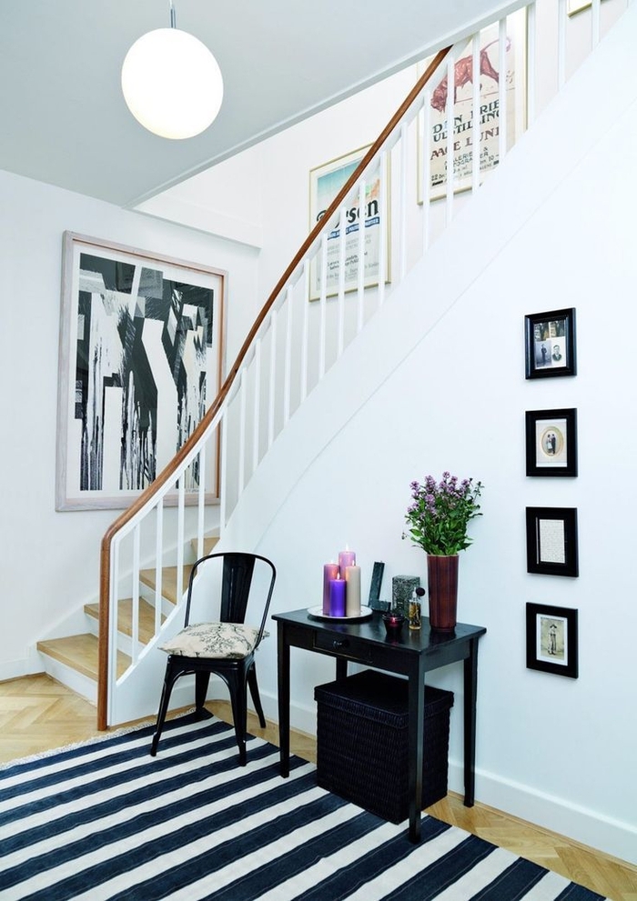 une galerie d'art aménagée dans une cage d'escalier étroite pour donner une touche arty dans le petit hall d'entrée en noir et blanc