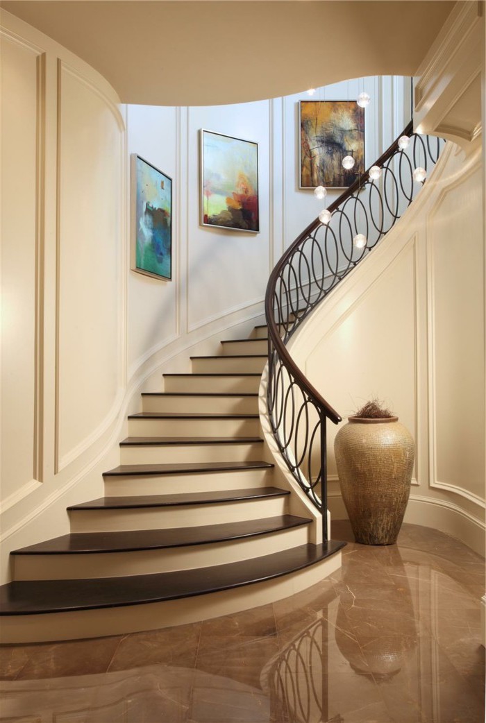 idées déco pour renover un escalier, montée d'escalier raffinée décorée de toiles élégante, avec un garde-corps en fer sculpté 