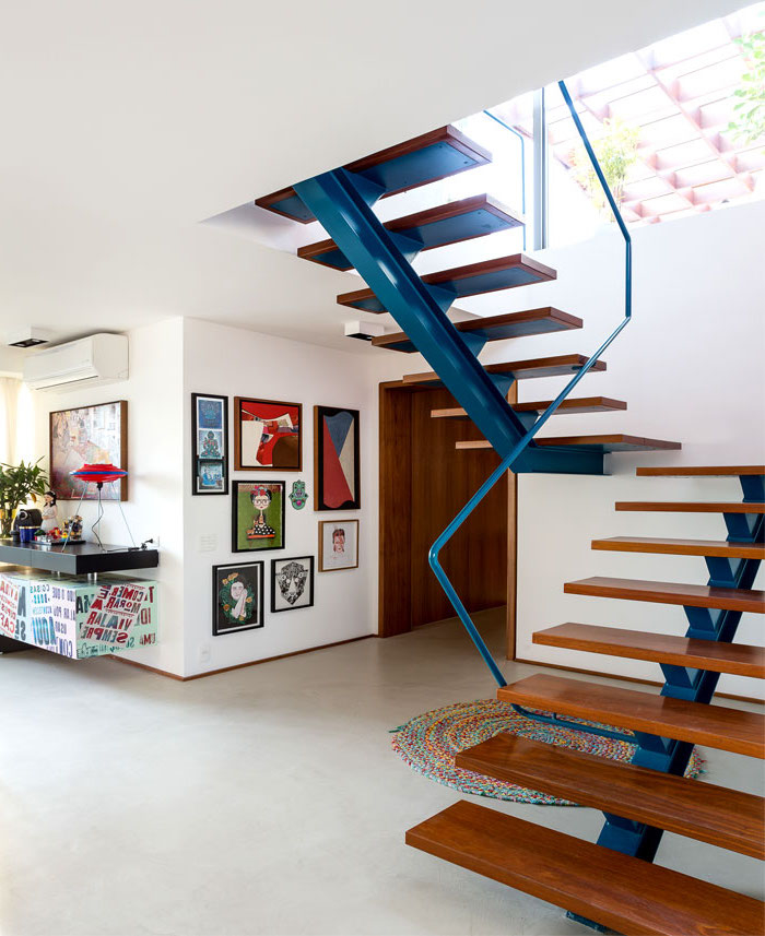 cage d'escalier d'esprit loft avec un limon métallique repeint en bleu supportant les marches en bois 