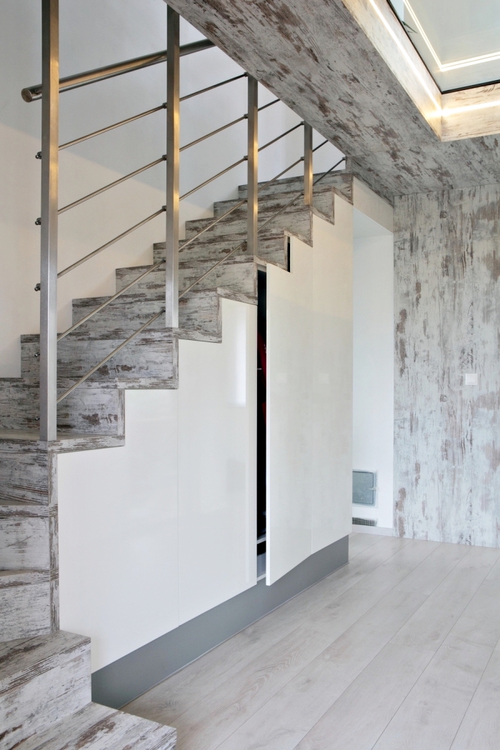 intérieur aux murs blancs avec revêtement de bois gris sur l'escalier et un amenagement sous pente