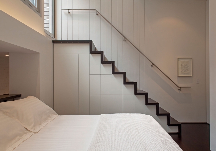 déco minimaliste dans la chambre à coucher blanche avec escalier en bois et rangement sous pente