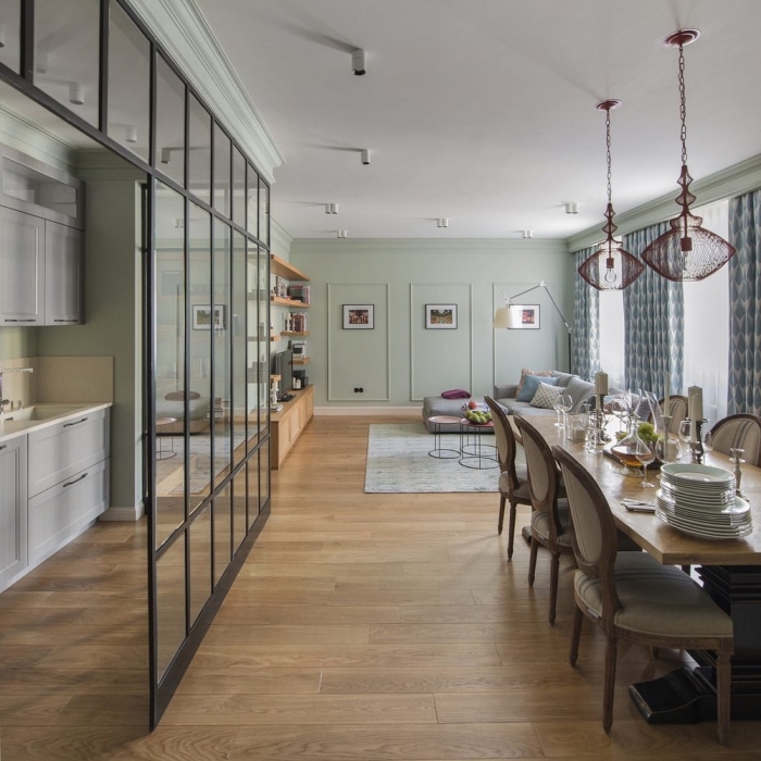 cuisine ouverte avec verrière, salle à manger et salon aux murs vert pastel et plafond blanc avec lampes suspendues violet