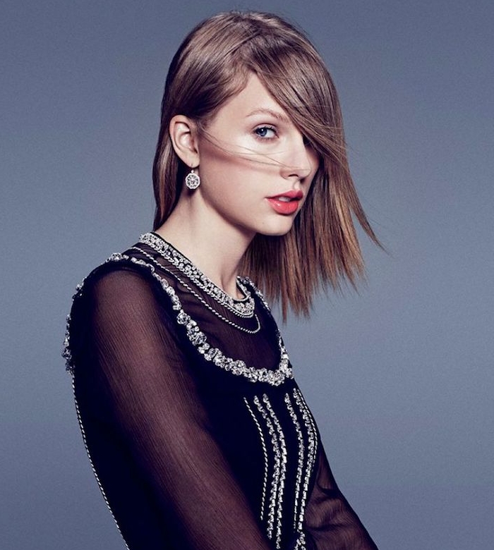 coupe-carre-plongeant-lisse-avec-frange-sur-le-front-robe-noire-stylée-taylor-swift-rouge-a-levres-rose taylor swift avec une coupe de cheveux carré plongeant lisse et long avec une mèche asymetrique sur le front, robe noire
