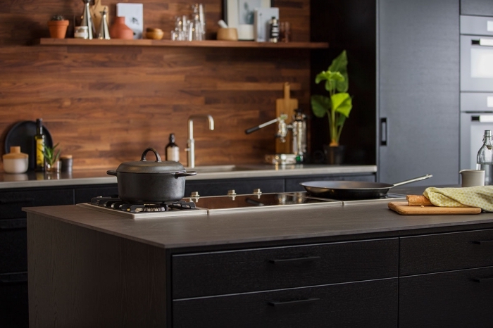 idée déco de cuisine moderne avec meubles noirs et crédence en bois marron foncé, cuisine noir mat