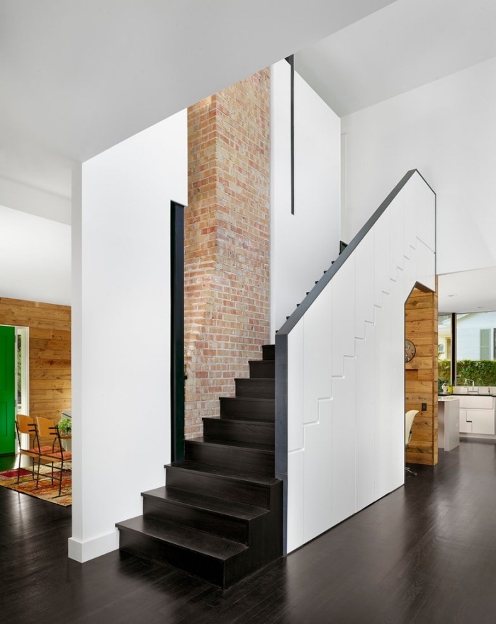 déco moderne en blanc et noir avec mur de briques rouges, meubles design avec rangement sous escalier coulissant