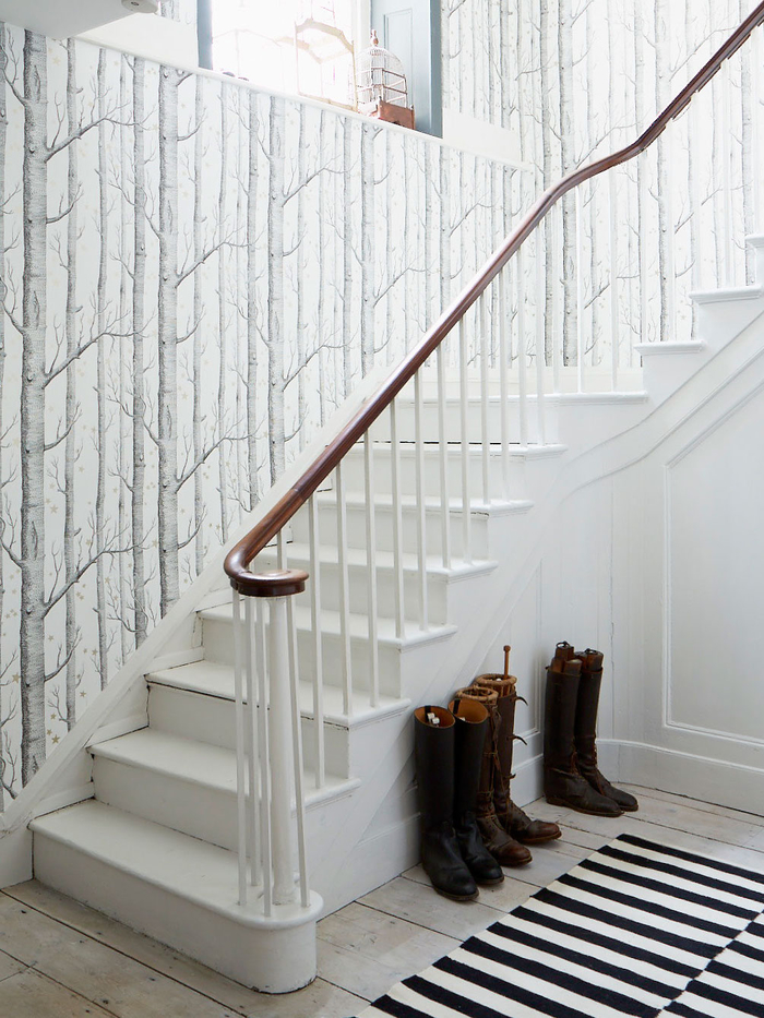 déco montée d'escalier de style nordique épuré avec un papier peint à motif arbre qui se fond avec l'escalier et le parquet blanc