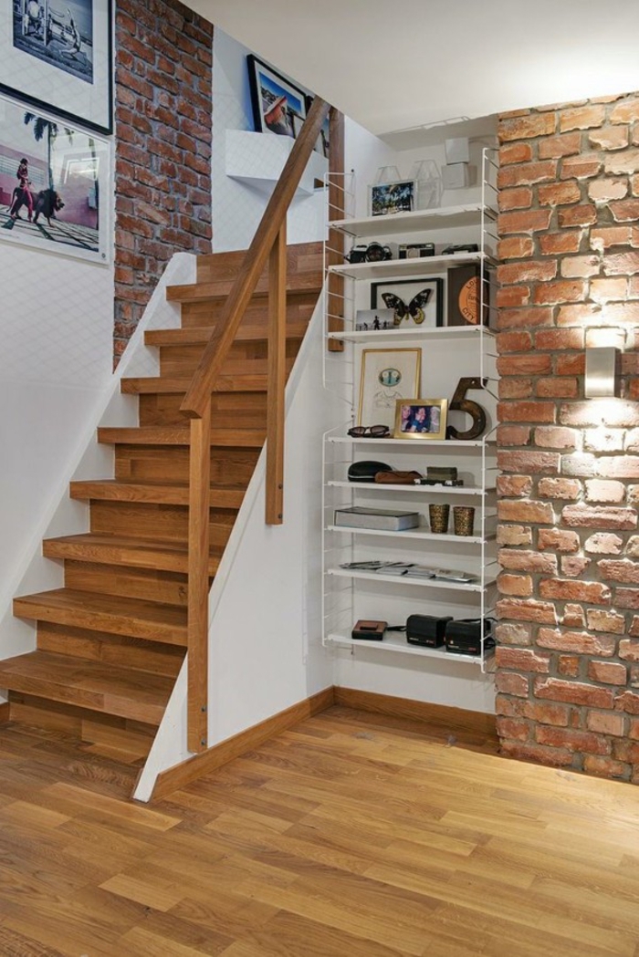 petit escalier en bois qui se fond dans la déco de la chambre, décoré d'un pan de mur en briques et des cadres photos