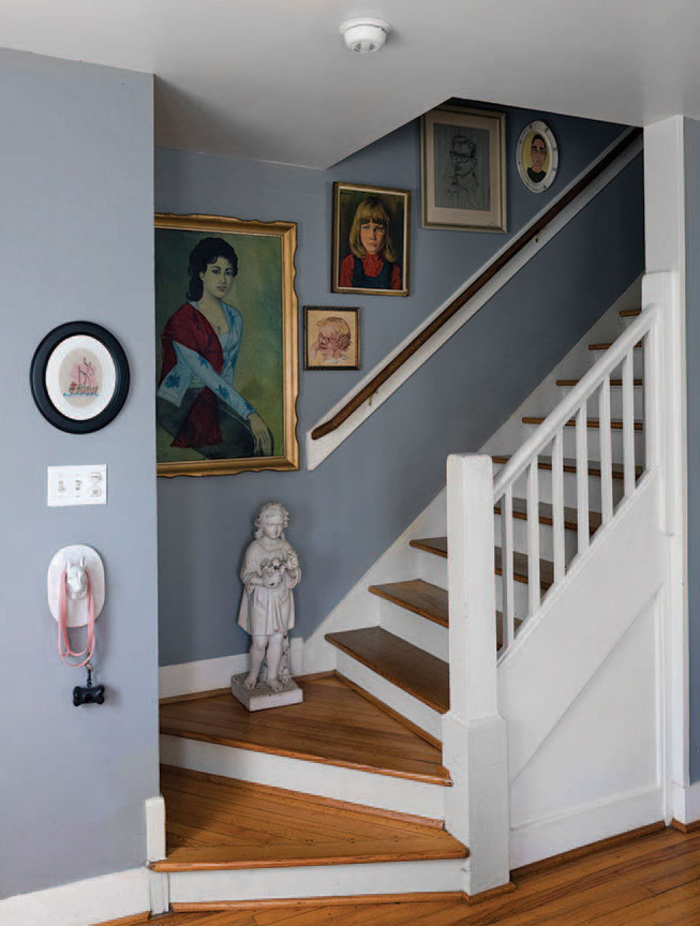 petit escalier repeint en nuance douce du bleu-gris en harmonie avec les contremarches et la balustrade blanches, décorée d'une galerie murale vintage