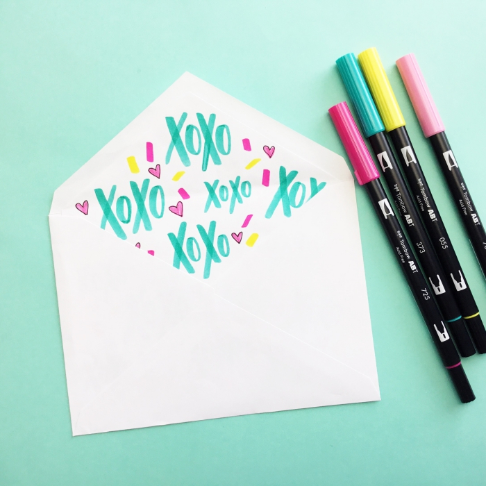 idée comment customiser une enveloppe blanche avec dessins et mots réalisés avec crayons en couleurs variées
