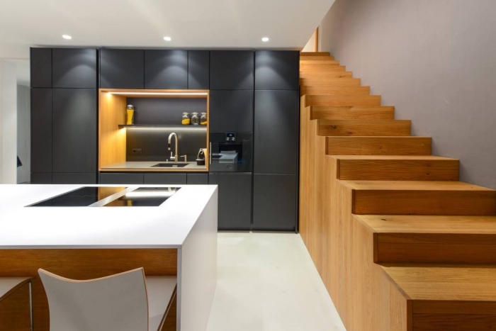 escalier moderne de bois dans une cuisine ouverte vers la salle à manger, cuisine ikea noire avec ilot central blanc
