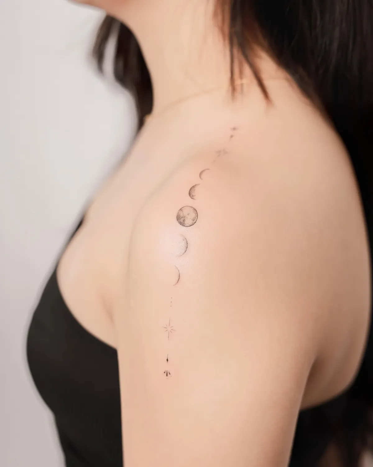 femme en top noir au tatouage astral sur l epaule phases de la lune