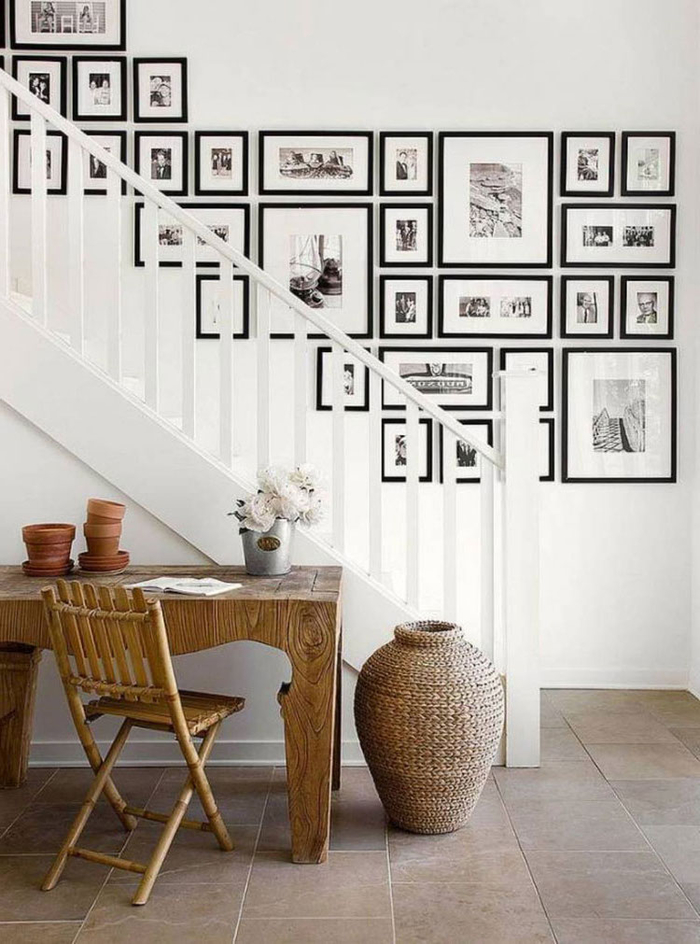 idée pour un mur en cadres photos noir et blanc disposés harmonieusement et en jolie contraste avec l'escalier repeint en blanc