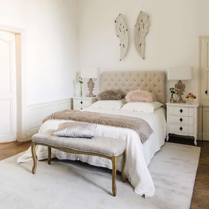peinture murale blanche dans la chambre adulte avec lit en tête beige boutonné et large tapis gris clair