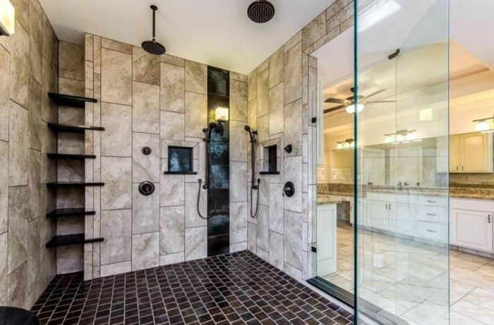 cabine de douche avec rangement mural, travertin aux murs, sol mosaique noir