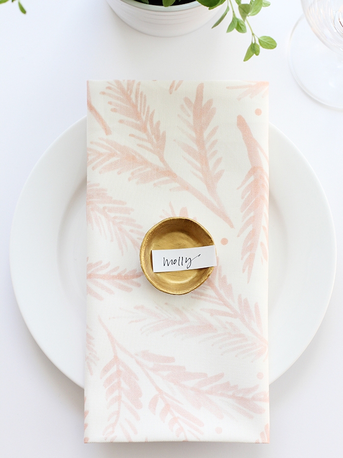 comment faire une marque place originale, modele pate fimo coupelle dorée avec étiquette contenant le nom de l'invité, serviette blanche à motif floral, déco table originale