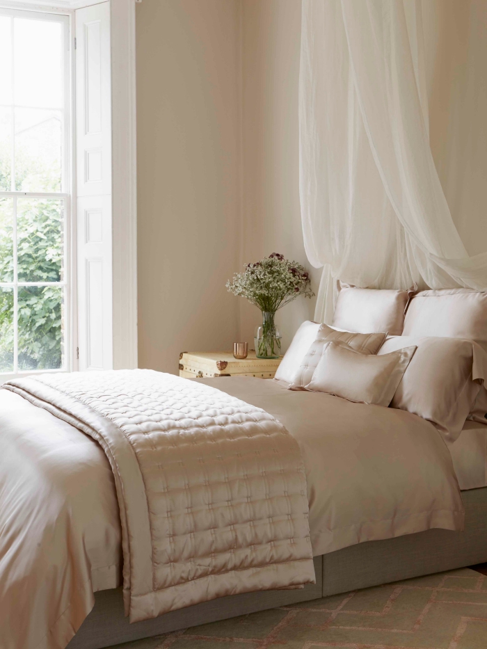 couleur pour chambre romantique aux murs beige et fenêtre blanche avec lit à baldaquin et table de chevet en bois clair