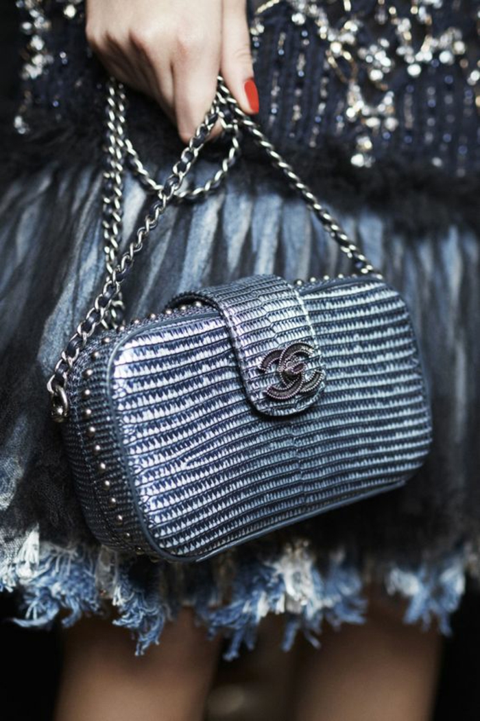 mini sac Chanel aux nuances irisées, avec le logo en métal noir, chaînette en métal couleur argent, jupe aux ourlets en petites plumes couleur blanche et grise, soirée chic et choc comment s habiller 