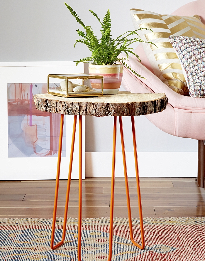 modele de table basse bois brut avec des pieds en metal orange et plateau en rondin de bois, accent rustique dans un salon feminin, canapé rose
