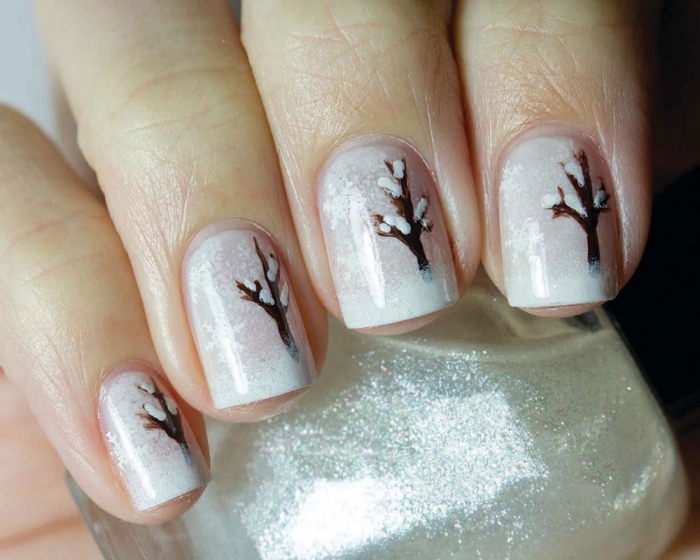 idée pour décoration ongles de Noel avec base blanche à effet enneigé et dessin d'arbre marron