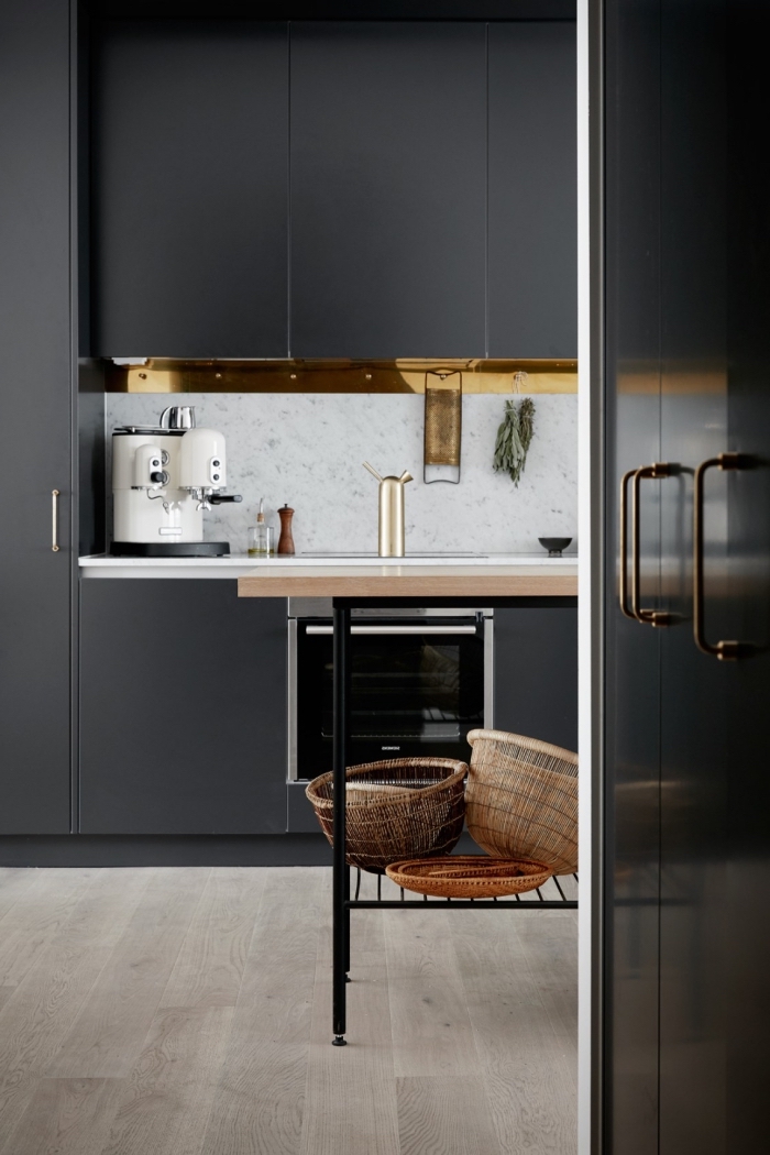 parquet stratifié de bois clair dans une cuisine à meubles noir matte avec crédence à design marbre blanc